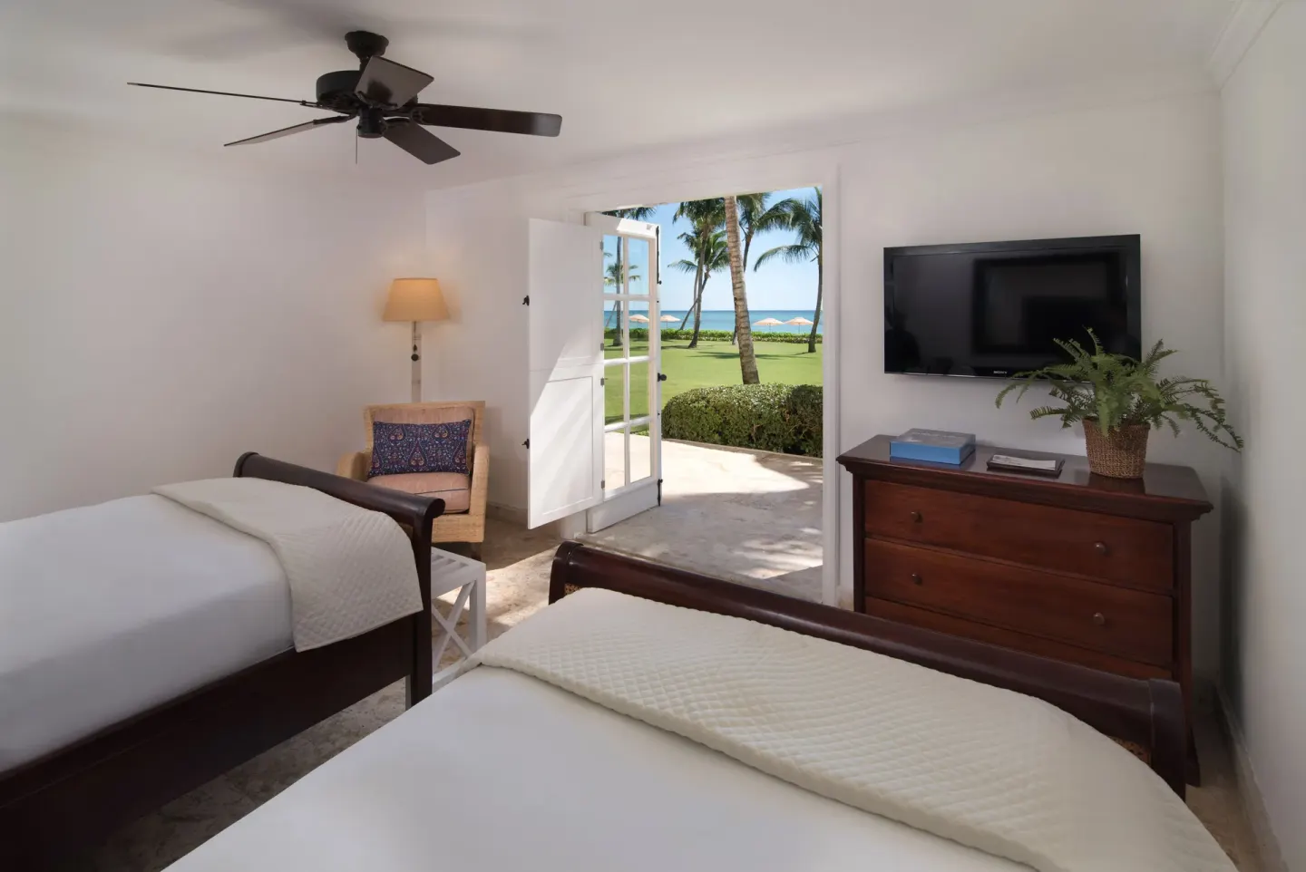 Twin bedroom at Tortuga Bay Hotel with open doors facing palms and ocean.