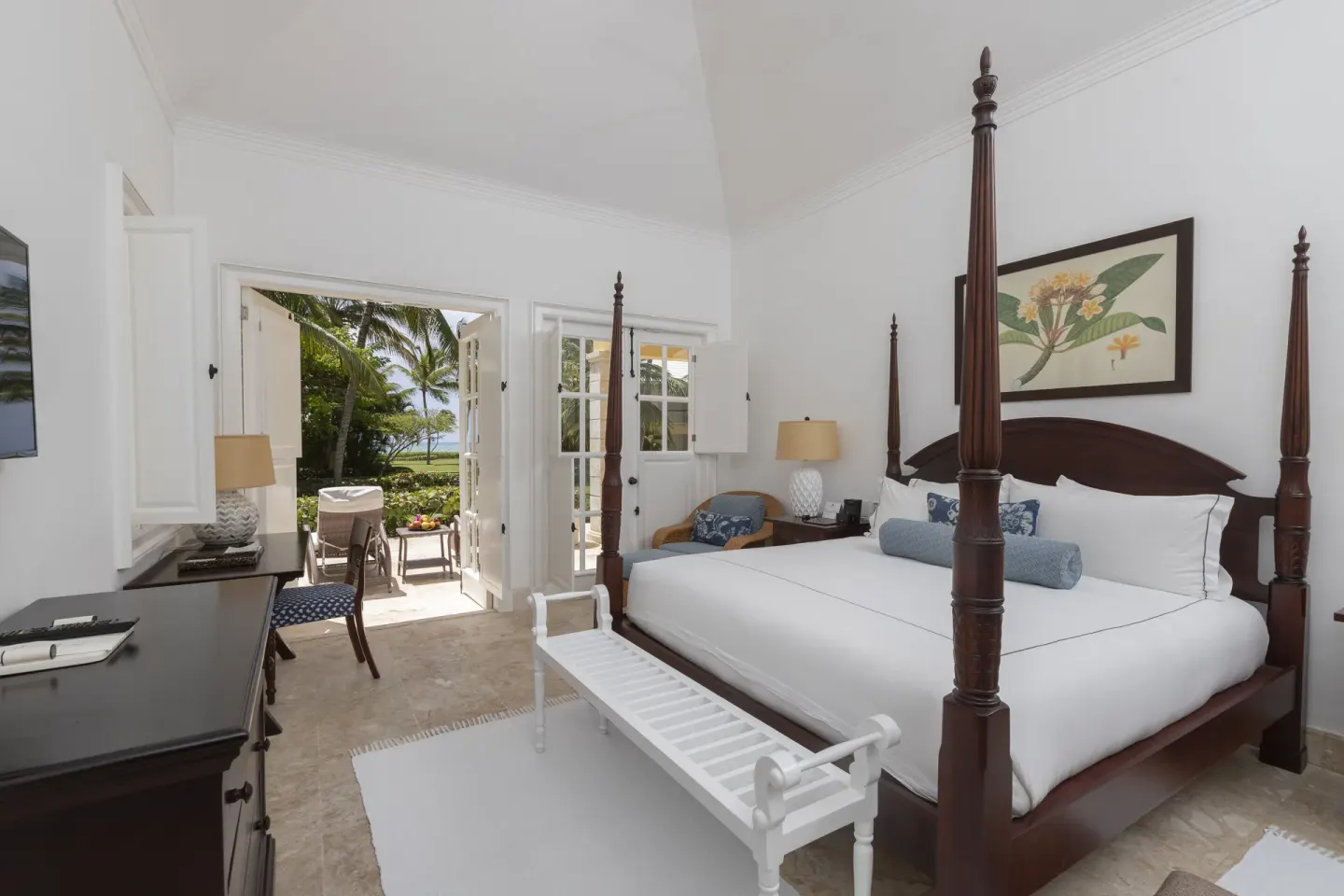 Four-poster king bedroom at Tortuga Bay Hotel opening to a patio and palms.