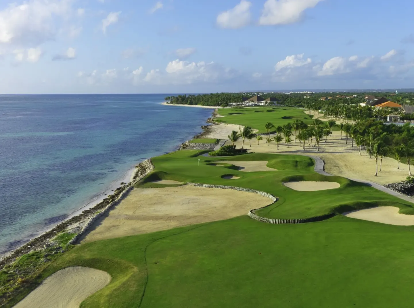 Aerial view of oceanfront golf greens and sand bunkers near Tortuga Bay Hotel.