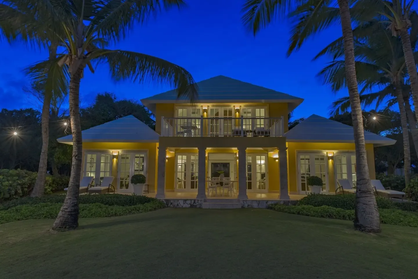 Illuminated yellow villa exterior at Tortuga Bay Hotel framed by palms at dusk.