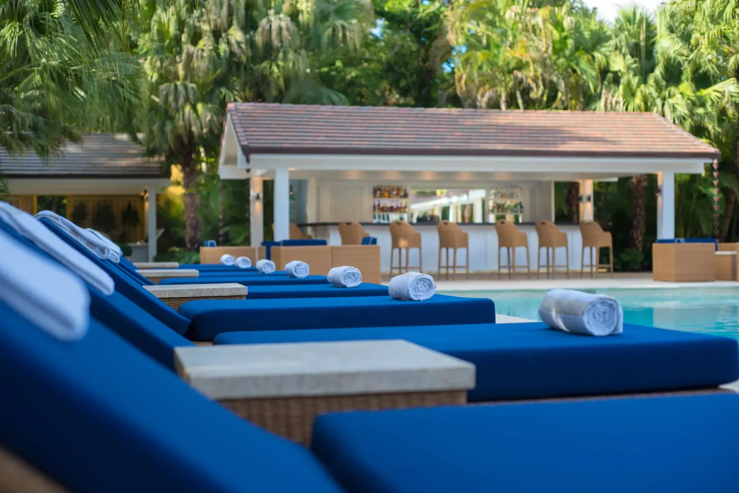 Blue pool loungers with towels face a swim-up bar at Tortuga Bay Hotel.