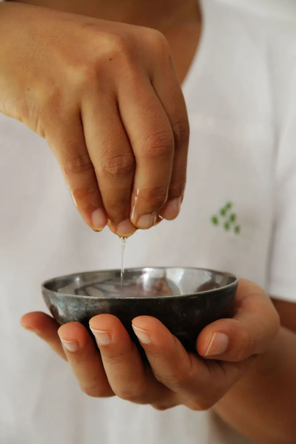 Hands squeeze liquid into a small spa bowl at Tortuga Bay Hotel.