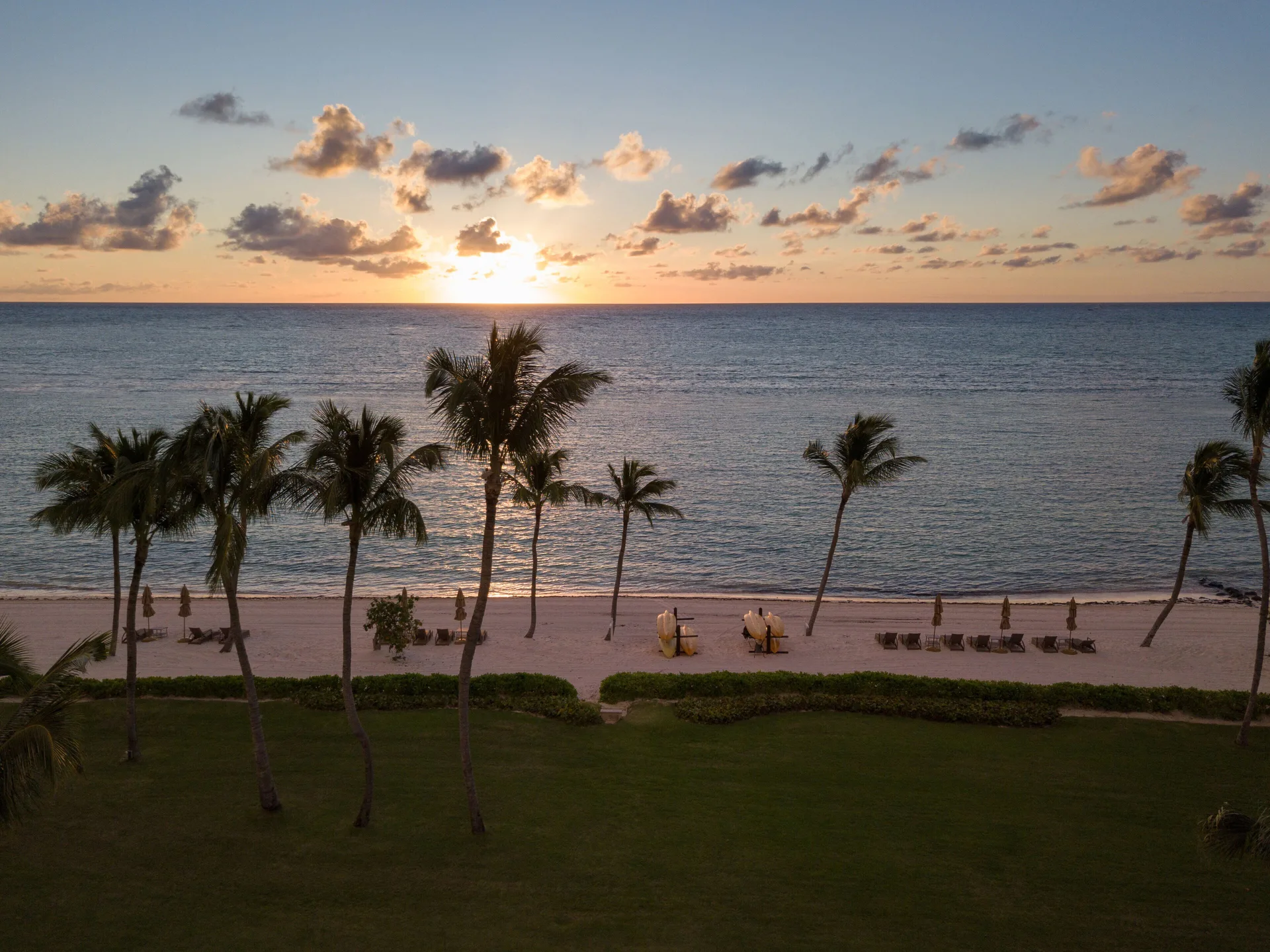 Sunrise over the beach, palms, loungers, and ocean at Tortuga Bay Hotel.