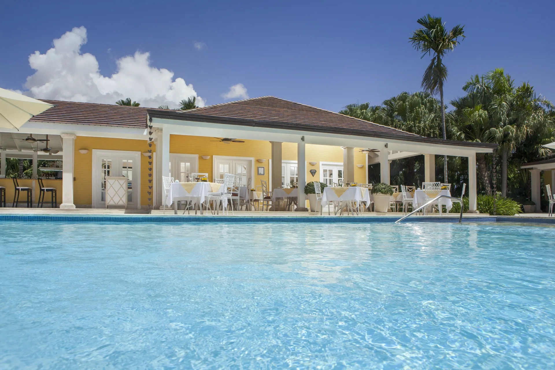 A poolside restaurant terrace overlooks clear blue water at Tortuga Bay Hotel.