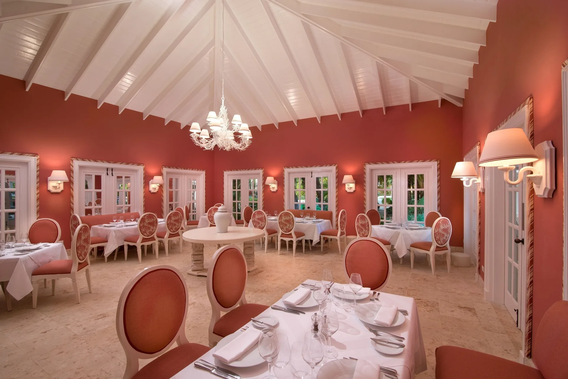 Wide coral dining room with vaulted ceiling and set tables at Tortuga Bay Hotel.