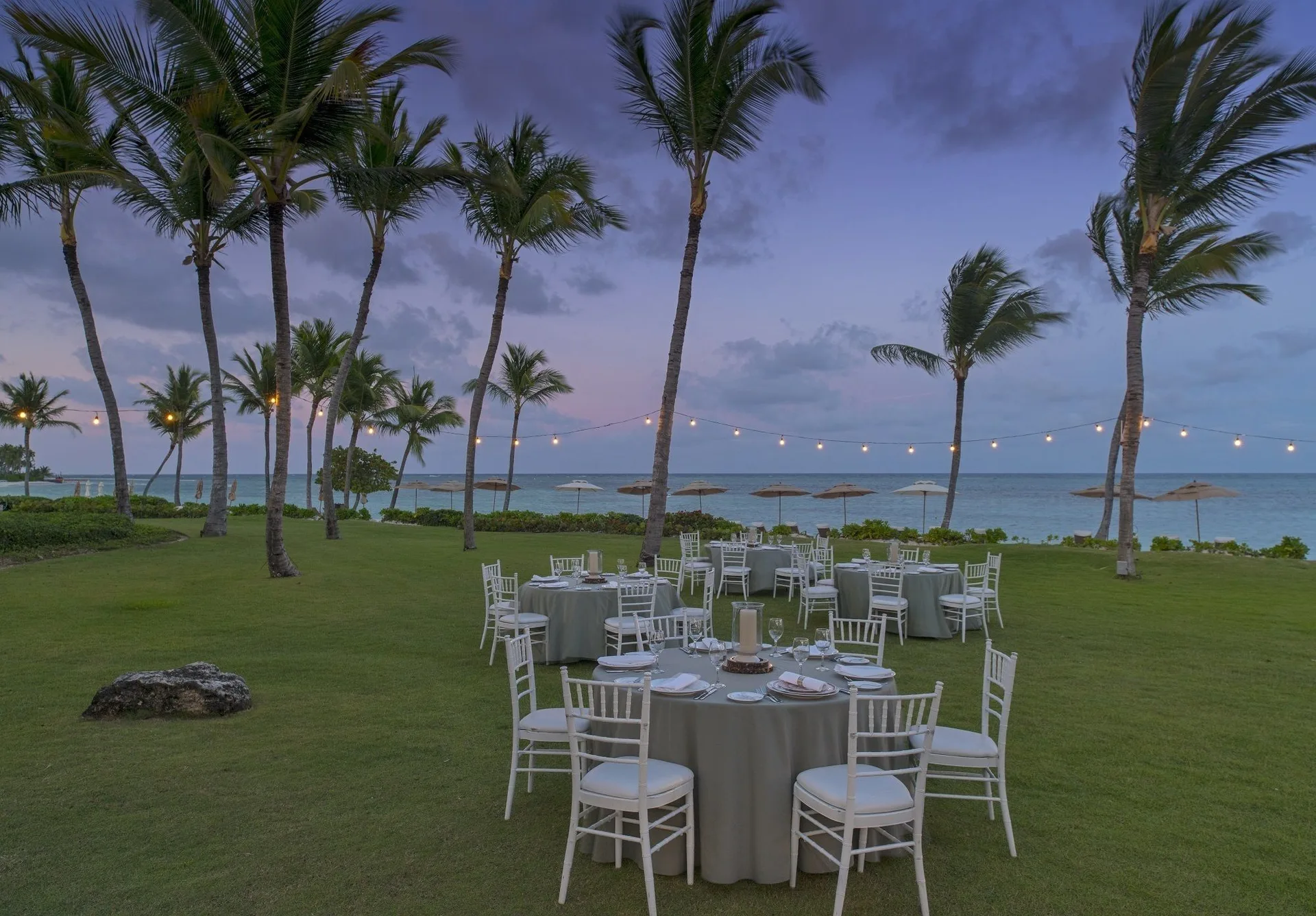 Oceanfront lawn dinner setup under palm trees at Tortuga Bay Hotel.