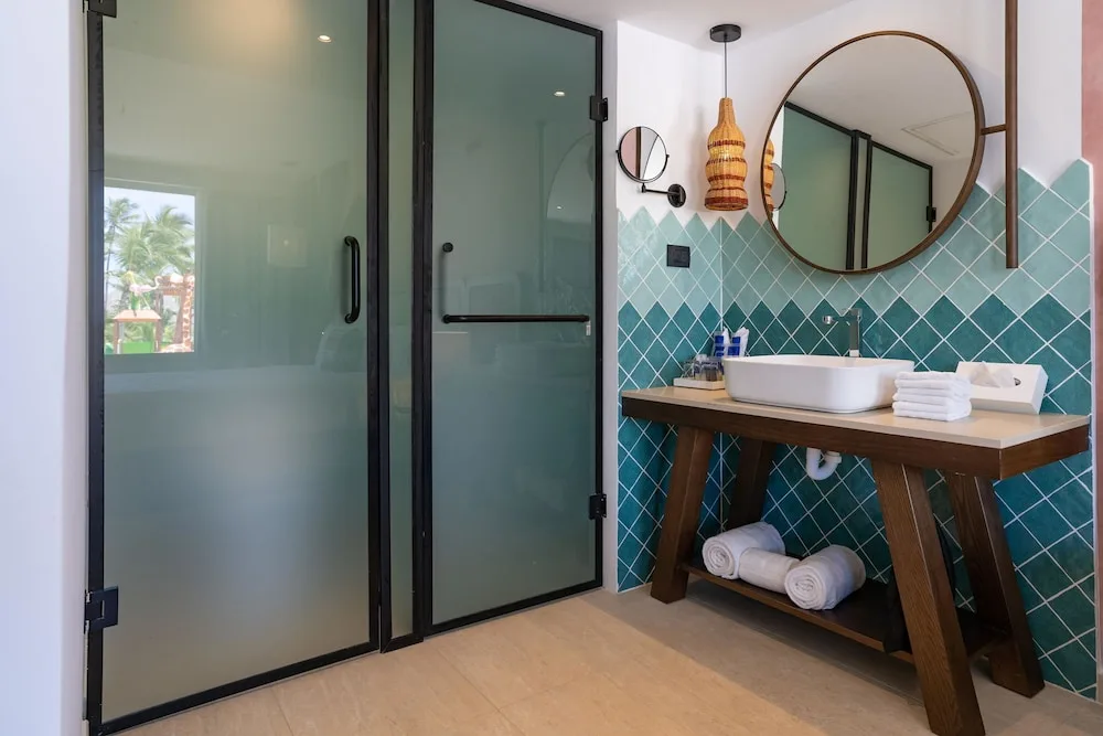 Bathroom vanity with turquoise tile and glass shower doors at Tropical Deluxe Princess.