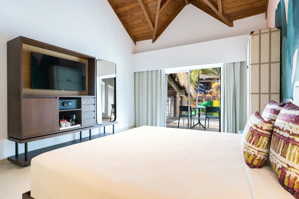 Guest room with king bed, balcony, and entertainment unit at Tropical Deluxe Princess.