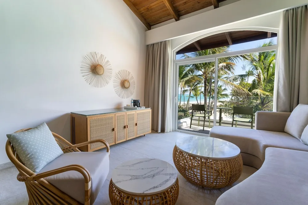 Guest room sitting area with balcony and palm view at Tropical Deluxe Princess.