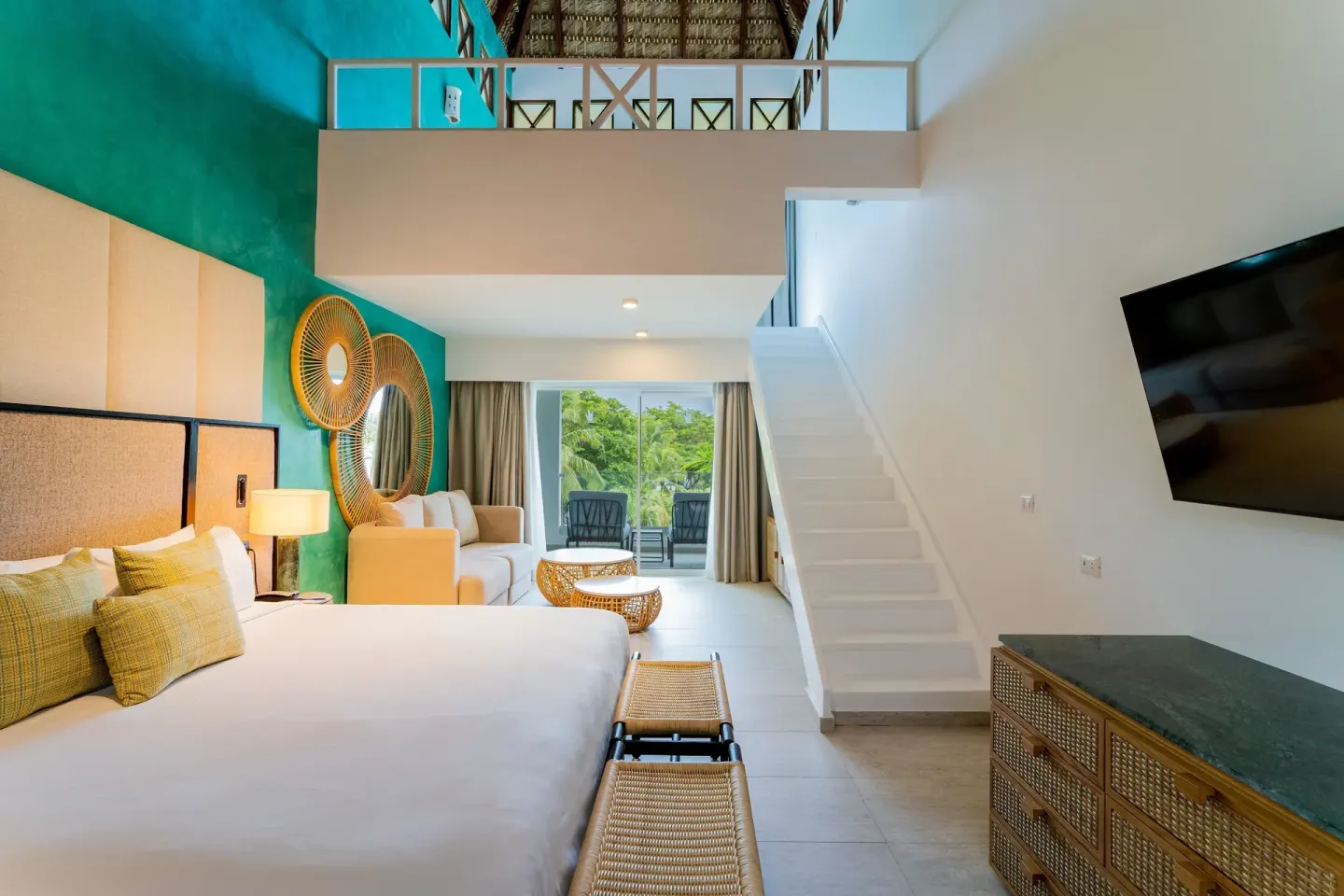 Loft-style guest room with king bed and staircase at Tropical Deluxe Princess.