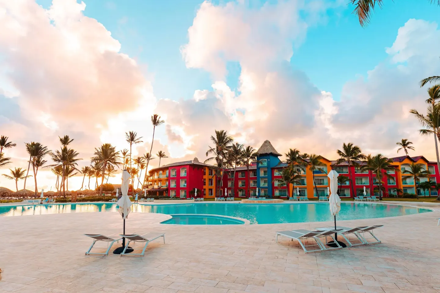 Large pool at sunset with colorful resort buildings at Tropical Deluxe Princess.