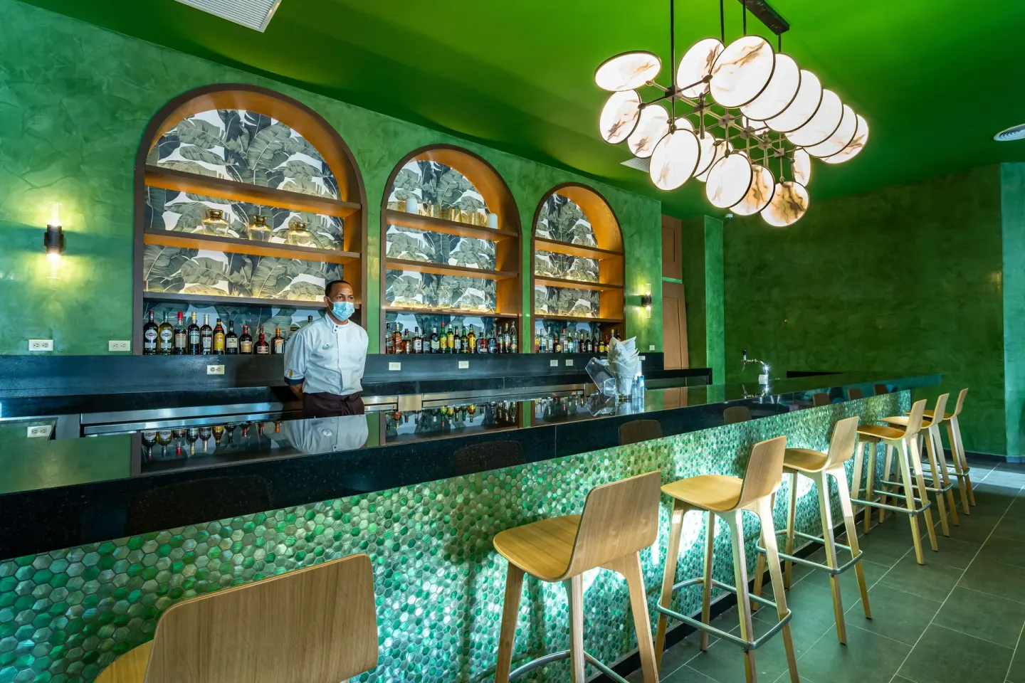 Green bar counter with stools and a bartender at Tropical Deluxe Princess.