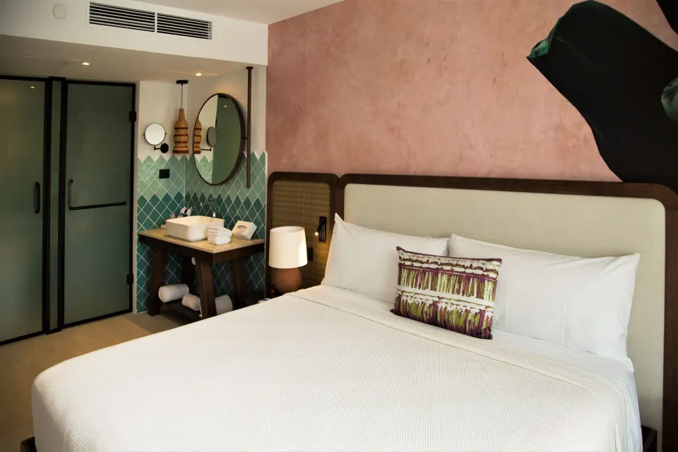 Family Room king bed beside turquoise-tiled vanity at Tropical Deluxe Princess.