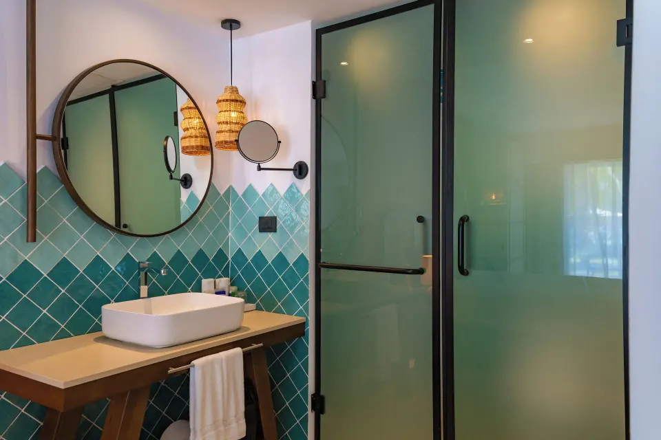 Superior Room bathroom vanity with teal tile and glass doors at Tropical Deluxe Princess.