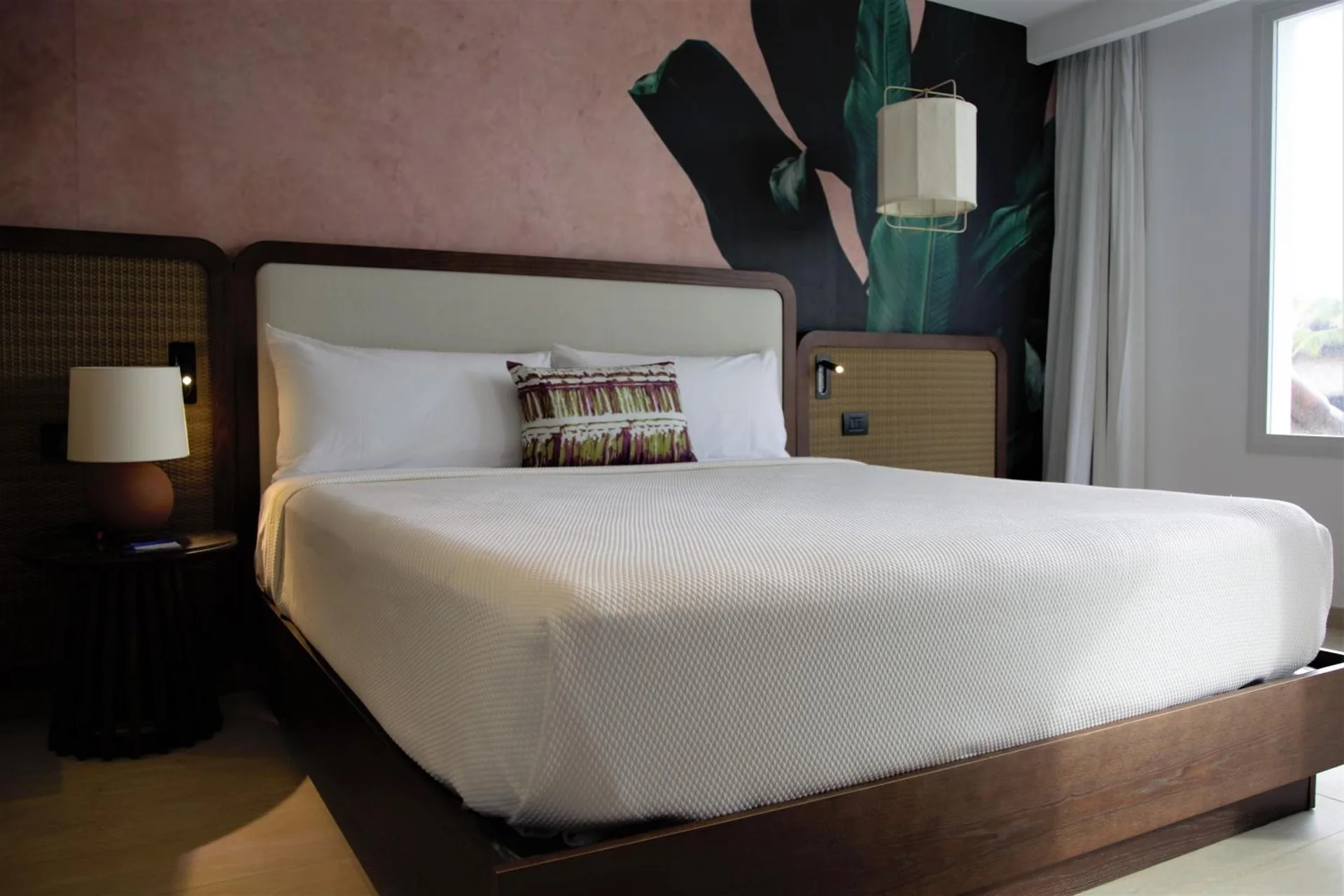 King bed with botanical wall art in a guest room at Tropical Deluxe Princess.