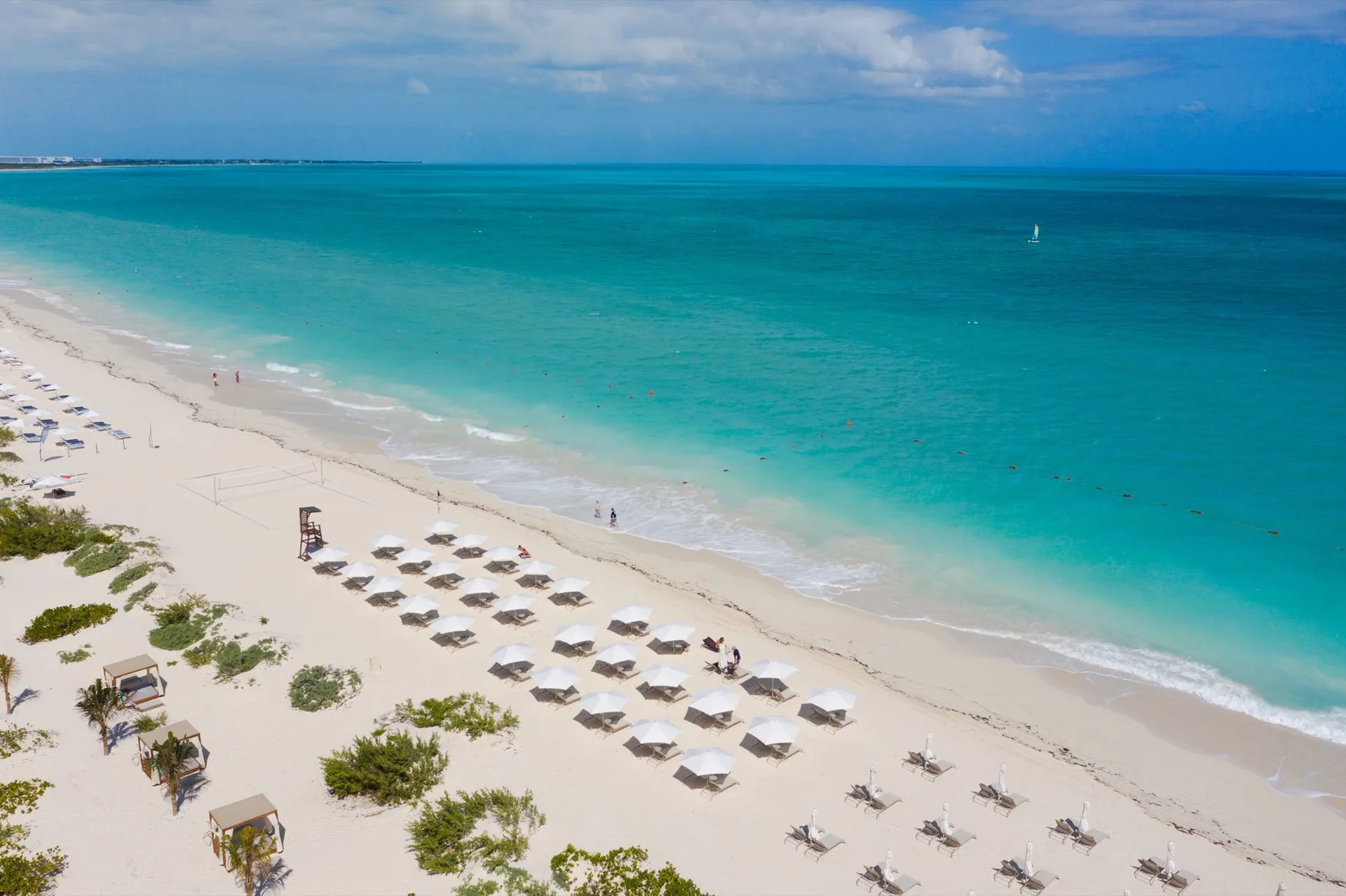 Aerial beach view with white umbrellas and turquoise water at TRS Coral Hotel.