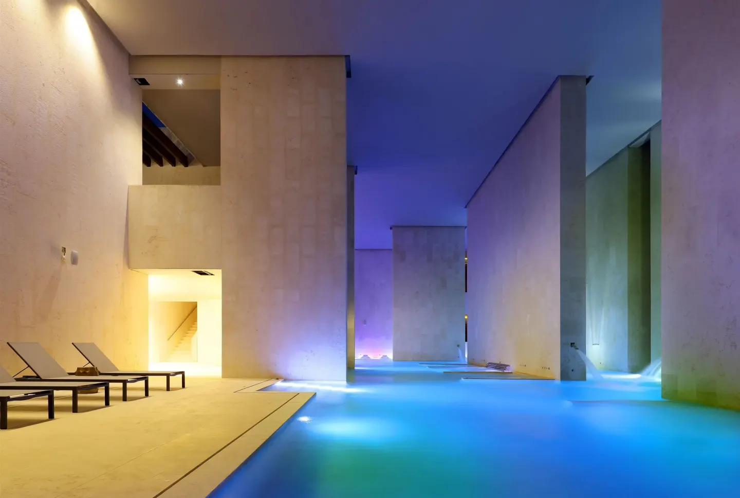 Indoor spa pool with blue water, stone walls and loungers at TRS Coral Hotel.