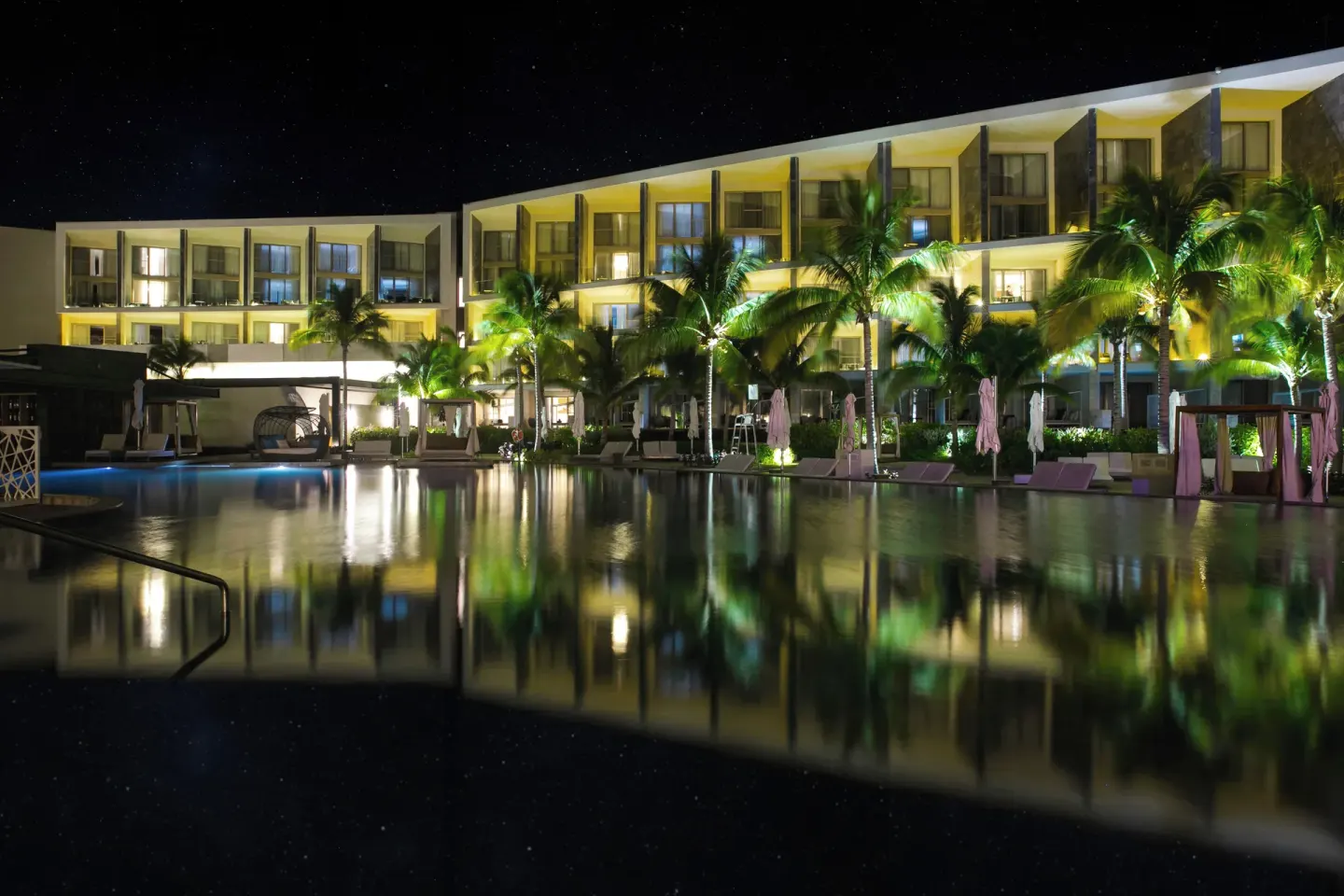 Night view of illuminated buildings reflected in the pool at TRS Coral Hotel.