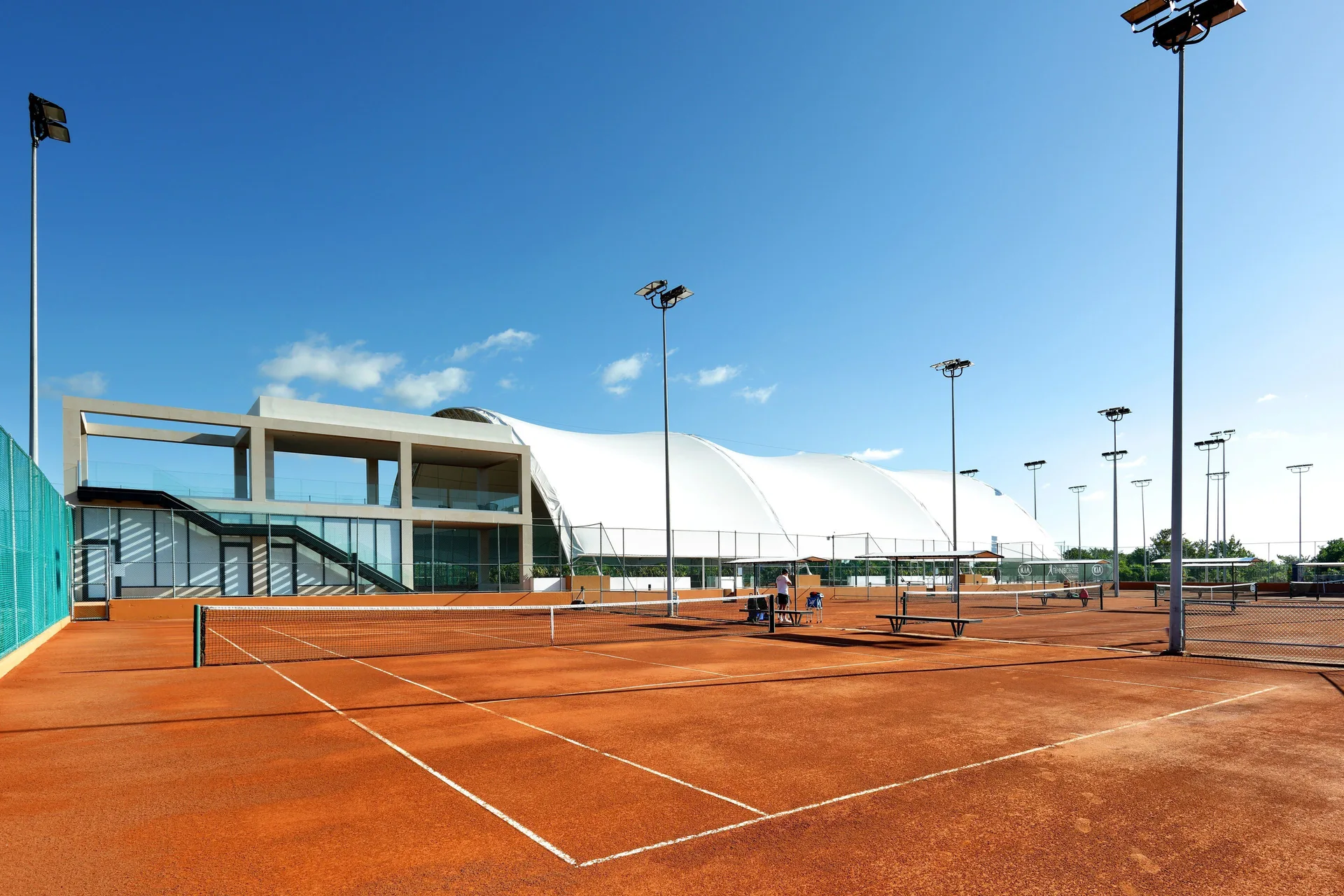 Outdoor clay tennis courts with lights and a clubhouse at TRS Coral Hotel.