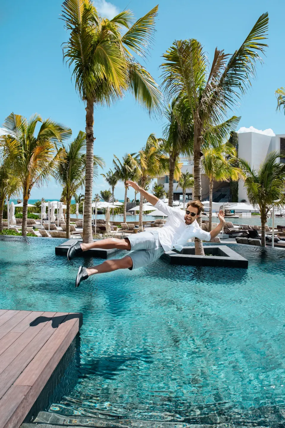 Man jumping into a palm-lined pool at TRS Coral Hotel.