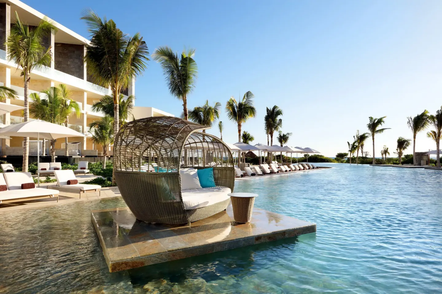 Poolside cabana over the water at TRS Coral Hotel with loungers, palms, and resort buildings.
