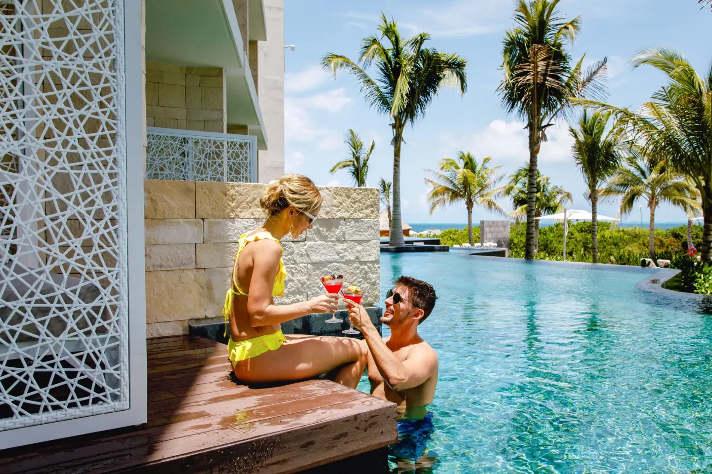 Couple toasting cocktails beside the pool at TRS Coral Hotel.