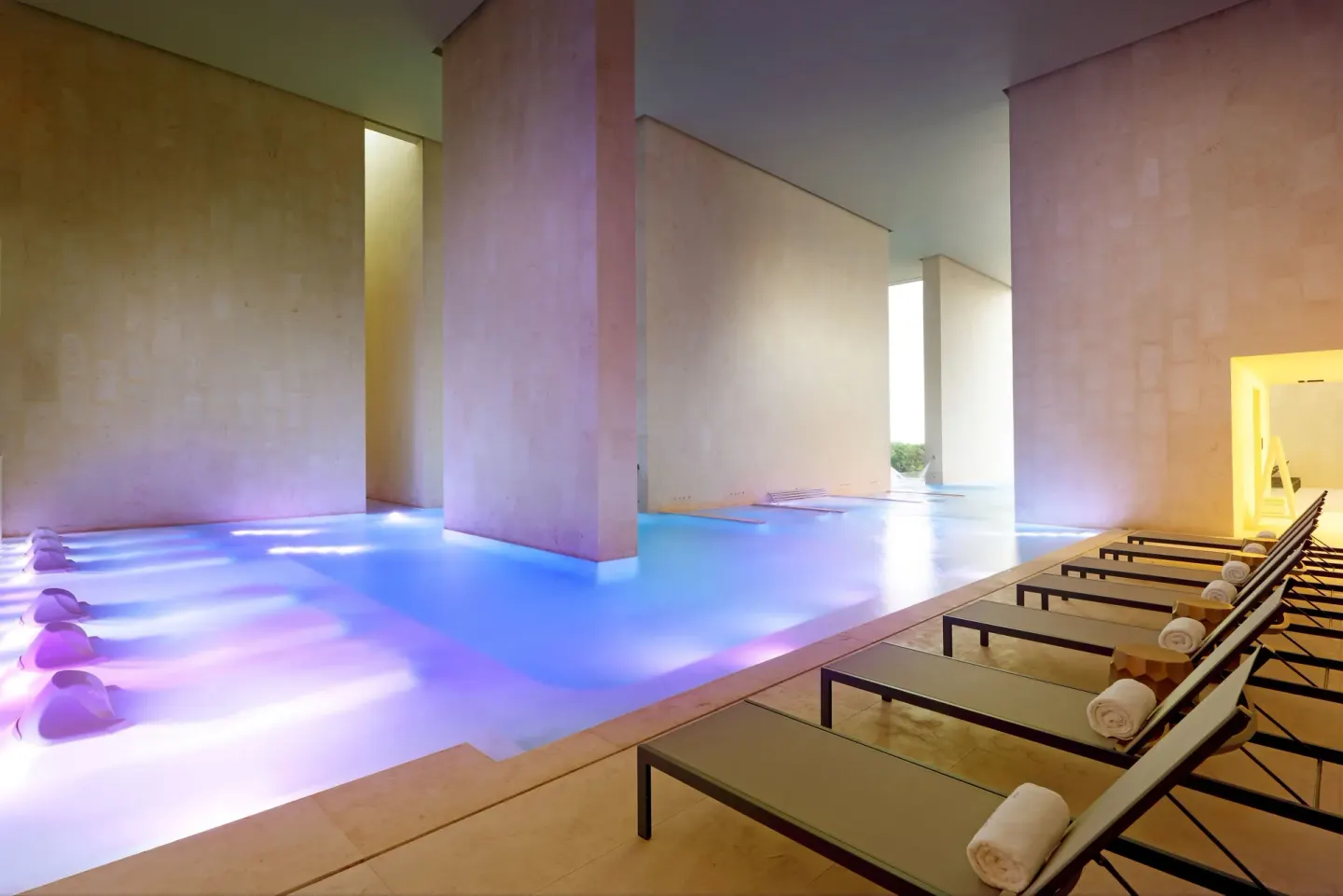 Spa pool with blue lighting, loungers and rolled towels at TRS Coral Hotel.