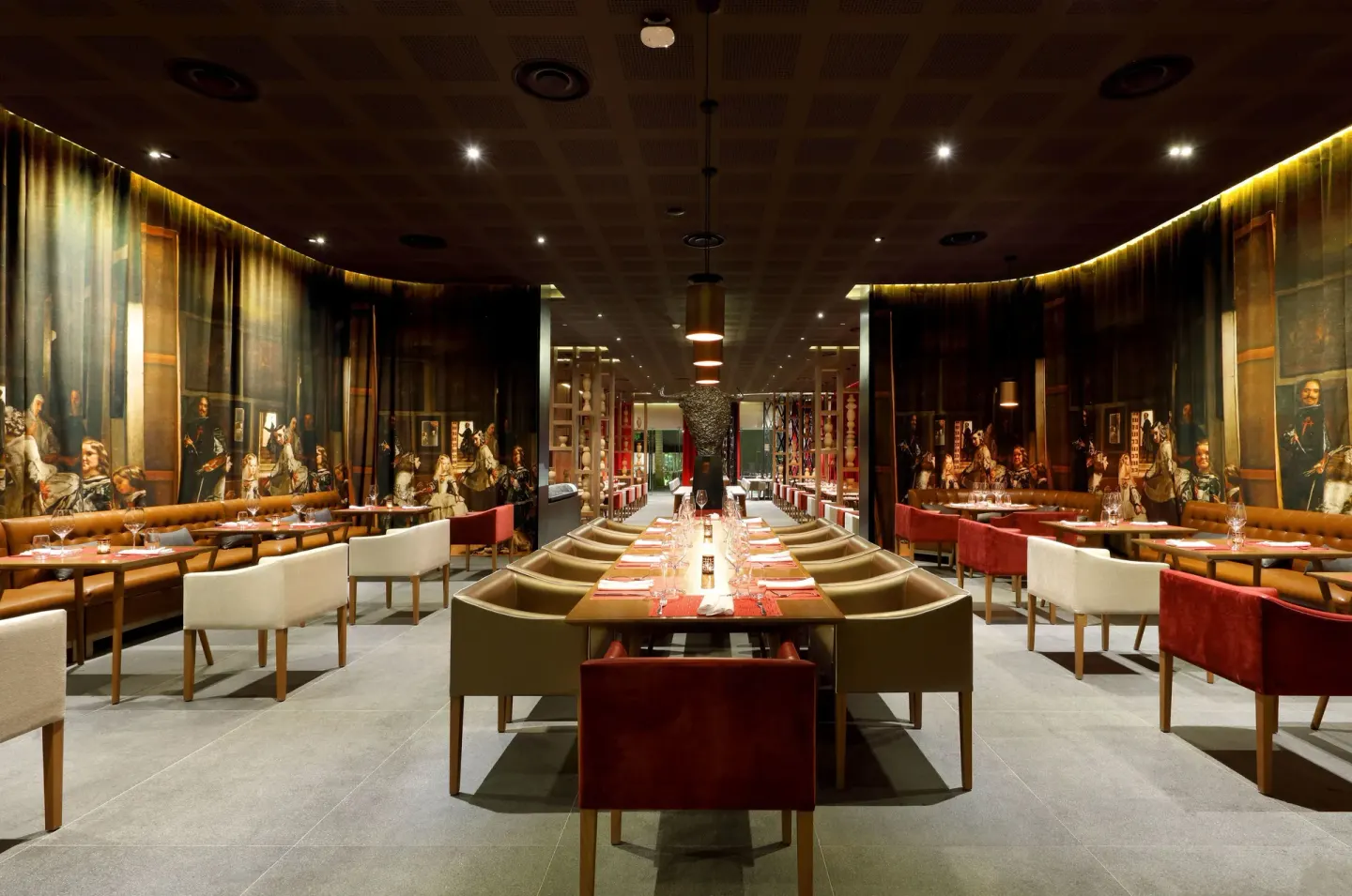 Steakhouse dining room with long tables and mural walls at TRS Coral Hotel.