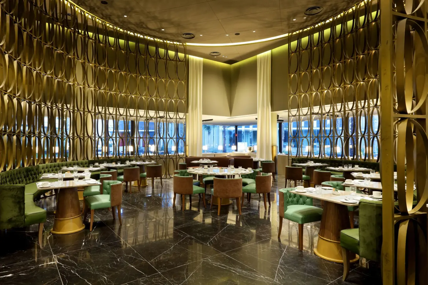 Elegant dining room with green seating and gold screen walls at TRS Coral Hotel.