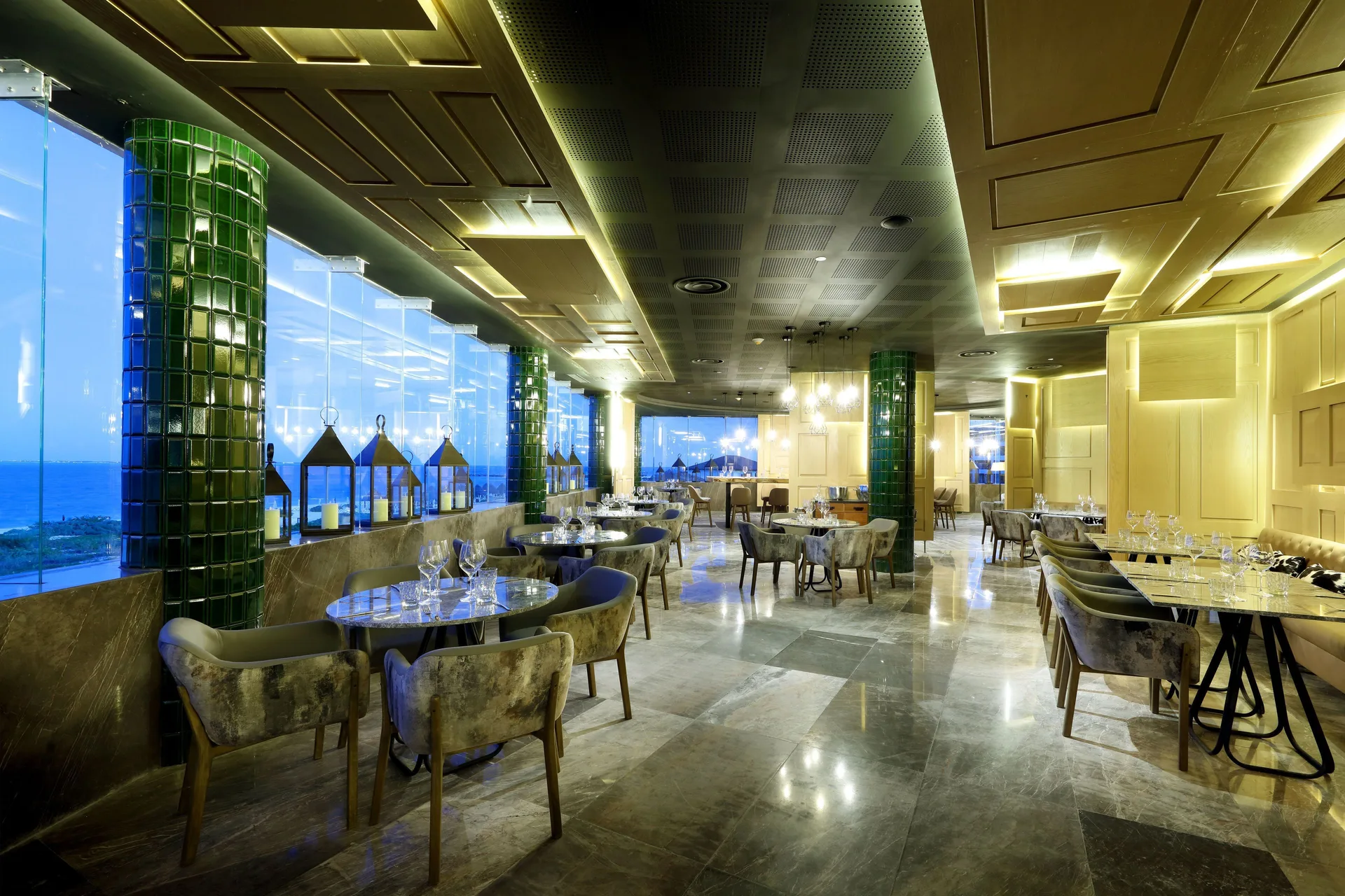 Ocean-view dining room with round tables and green columns at TRS Coral Hotel.
