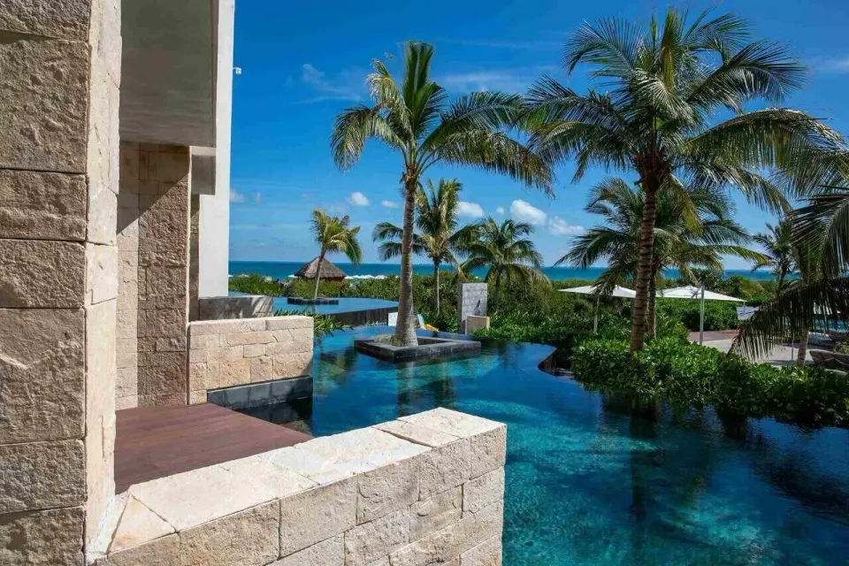 A swim-out terrace overlooks palm trees, pools, and the sea at TRS Coral Hotel.