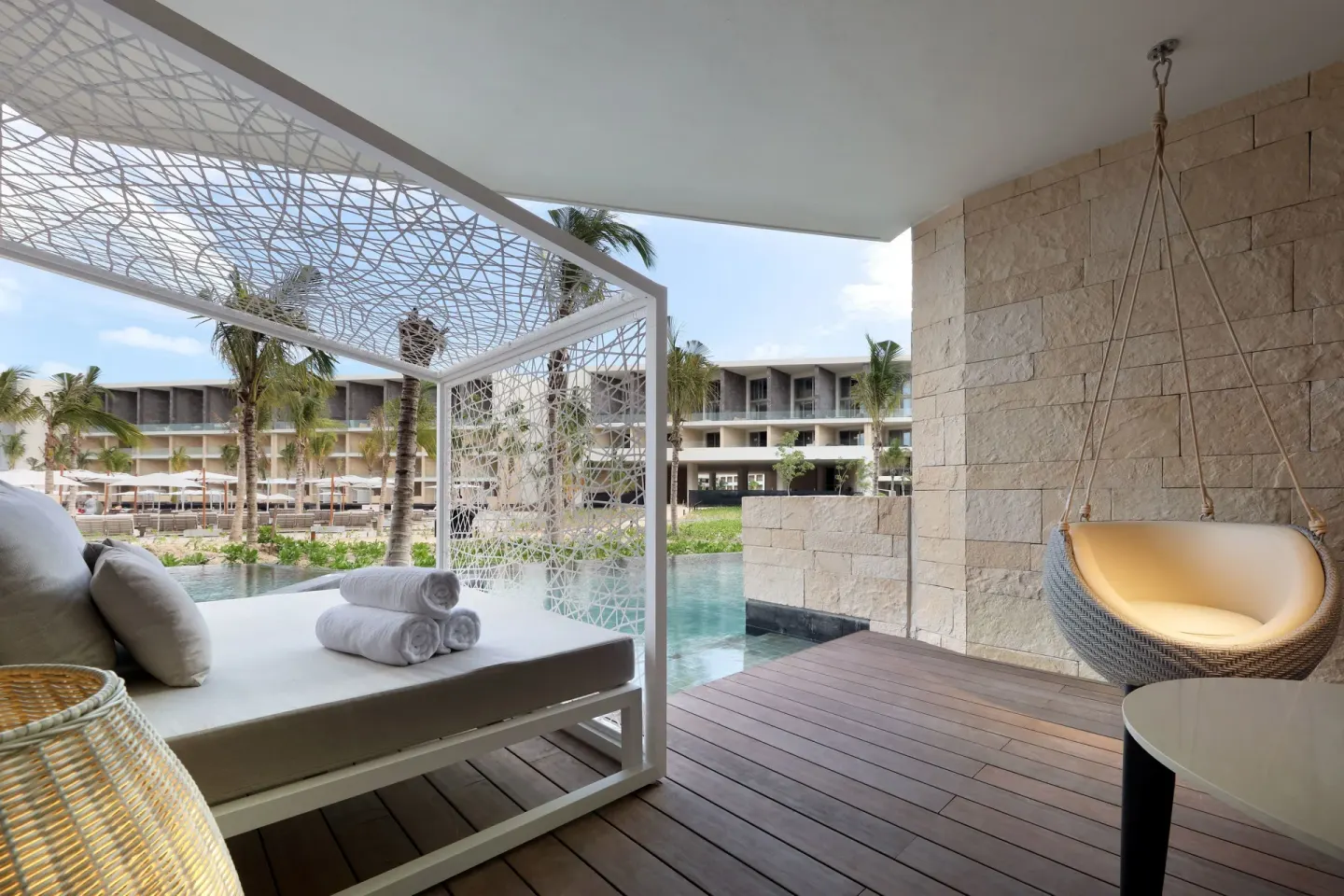 A shaded Junior Suite Swim Out terrace has a daybed and hanging chair at TRS Coral Hotel.