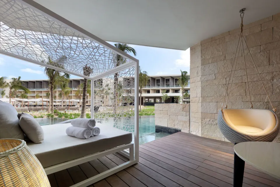 A shaded Junior Suite Swim Out terrace has a daybed and hanging chair at TRS Coral Hotel.