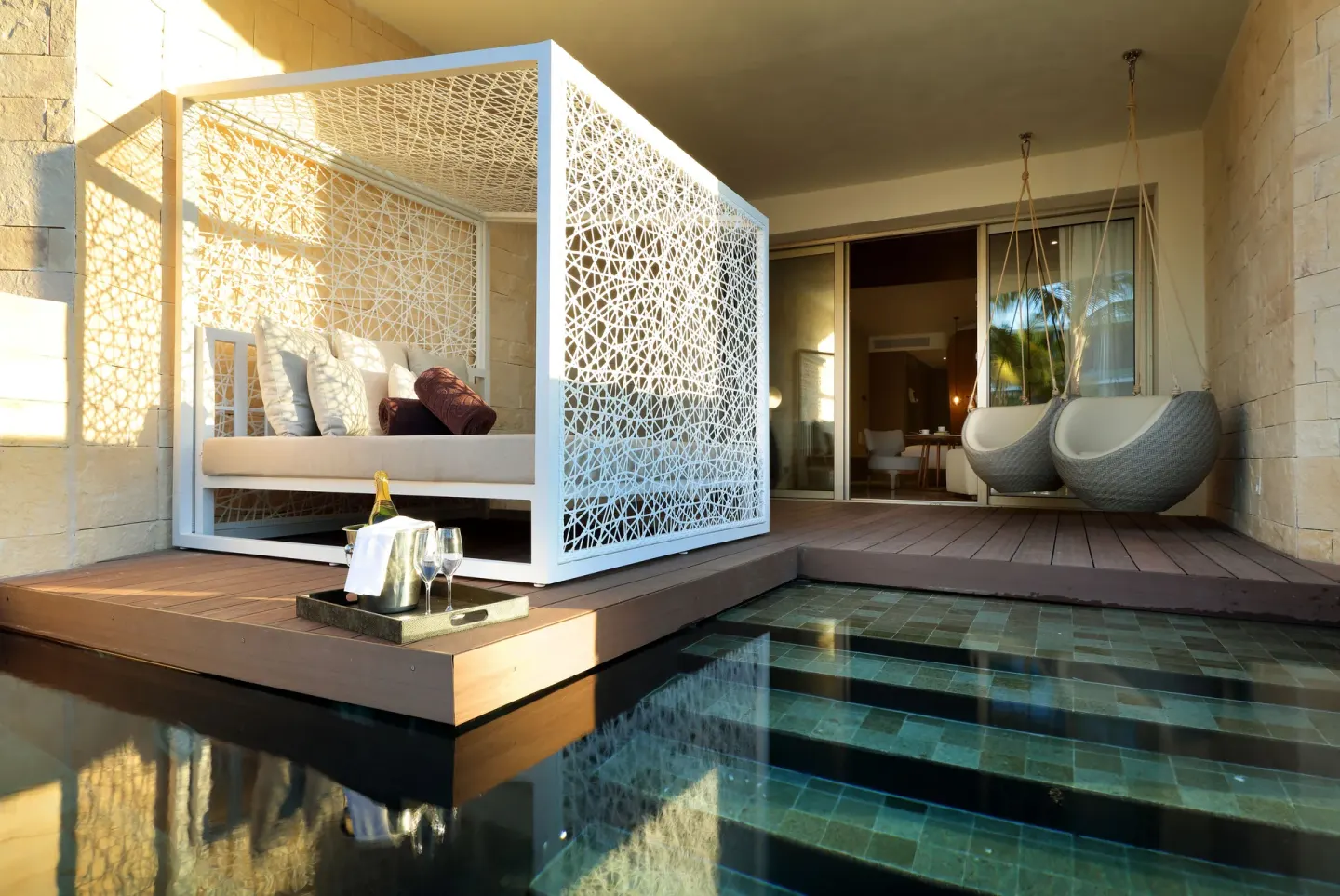 A Junior Suite Swim Out terrace has a daybed, hanging chairs, and pool steps at TRS Coral Hotel.