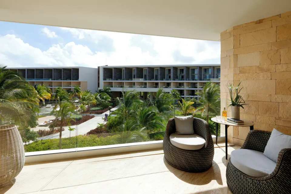 Junior Suite balcony seating overlooking palms and resort buildings at TRS Coral Hotel.