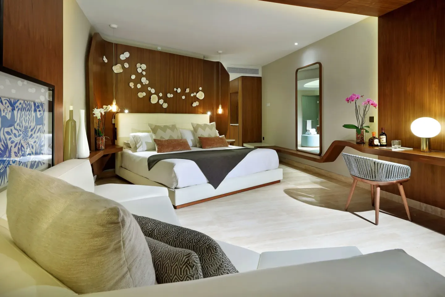 Junior Suite bedroom with king bed, sofa, desk, and wood accents at TRS Coral Hotel.
