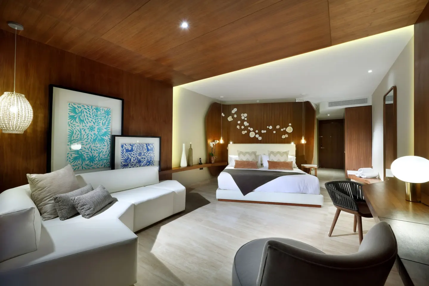 Junior Suite with king bed, white sectional sofa, desk, and wood ceiling at TRS Coral Hotel.