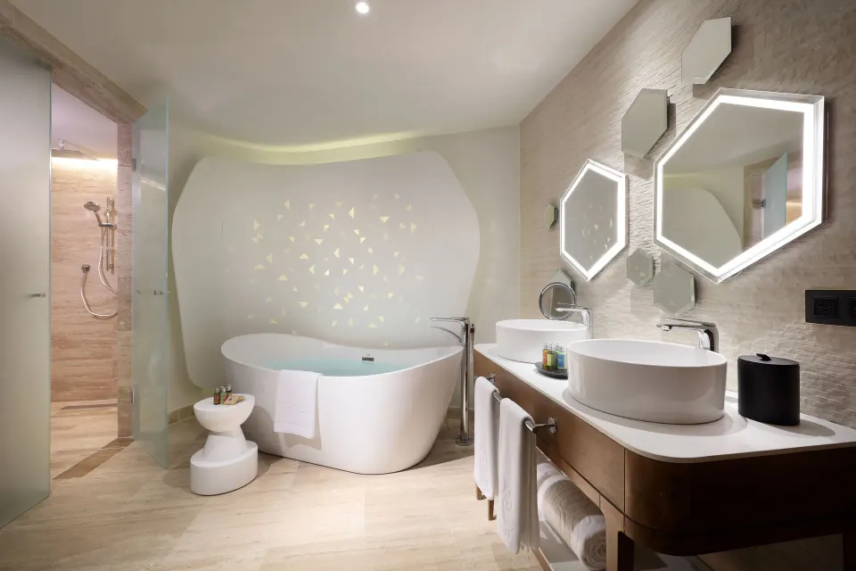 Loft Suite bathroom at TRS Coral Hotel with soaking tub, double sinks, lit mirrors, and glass shower.