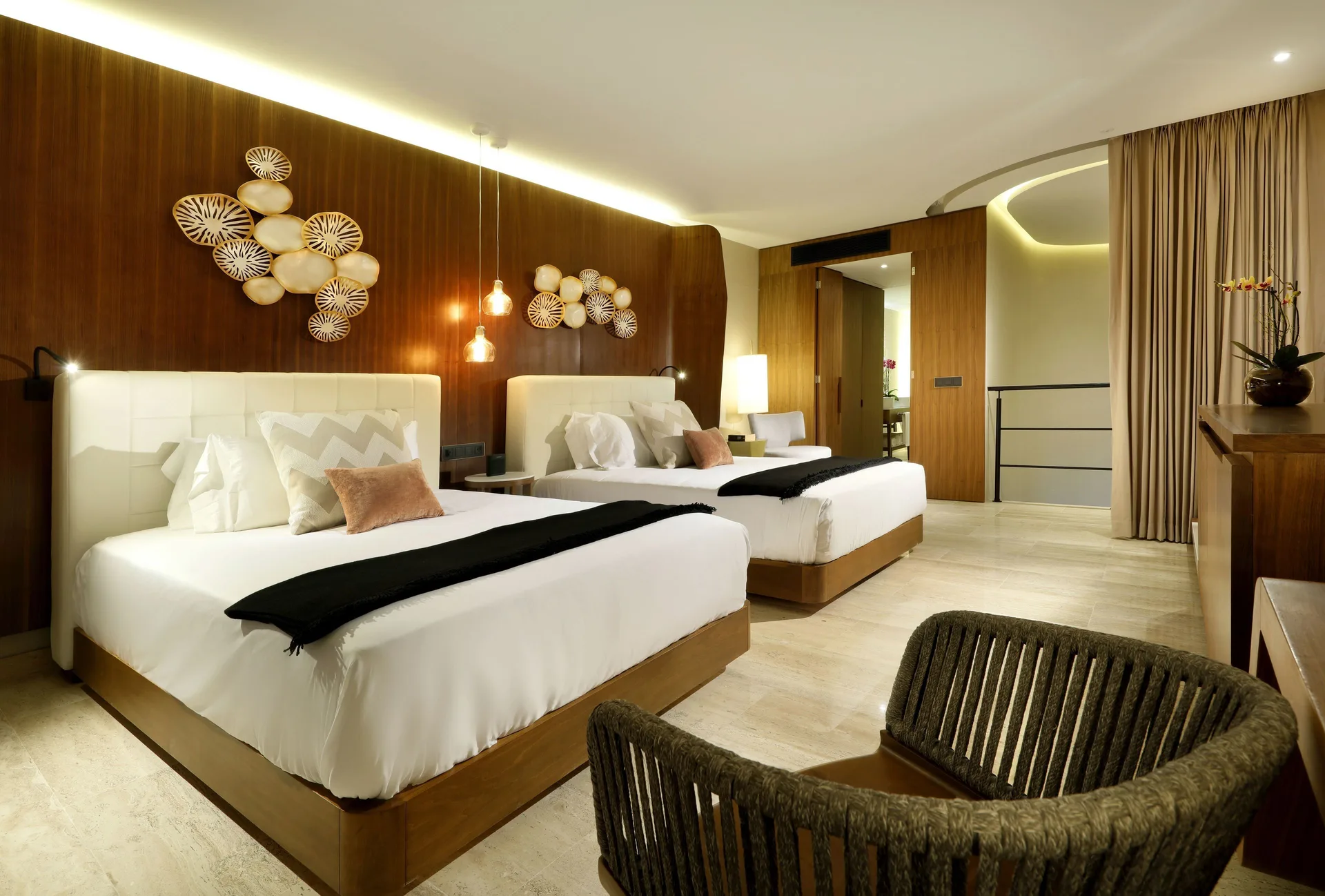 Loft Suite bedroom at TRS Coral Hotel with two beds, wood accent wall, pendant lights, and seating.