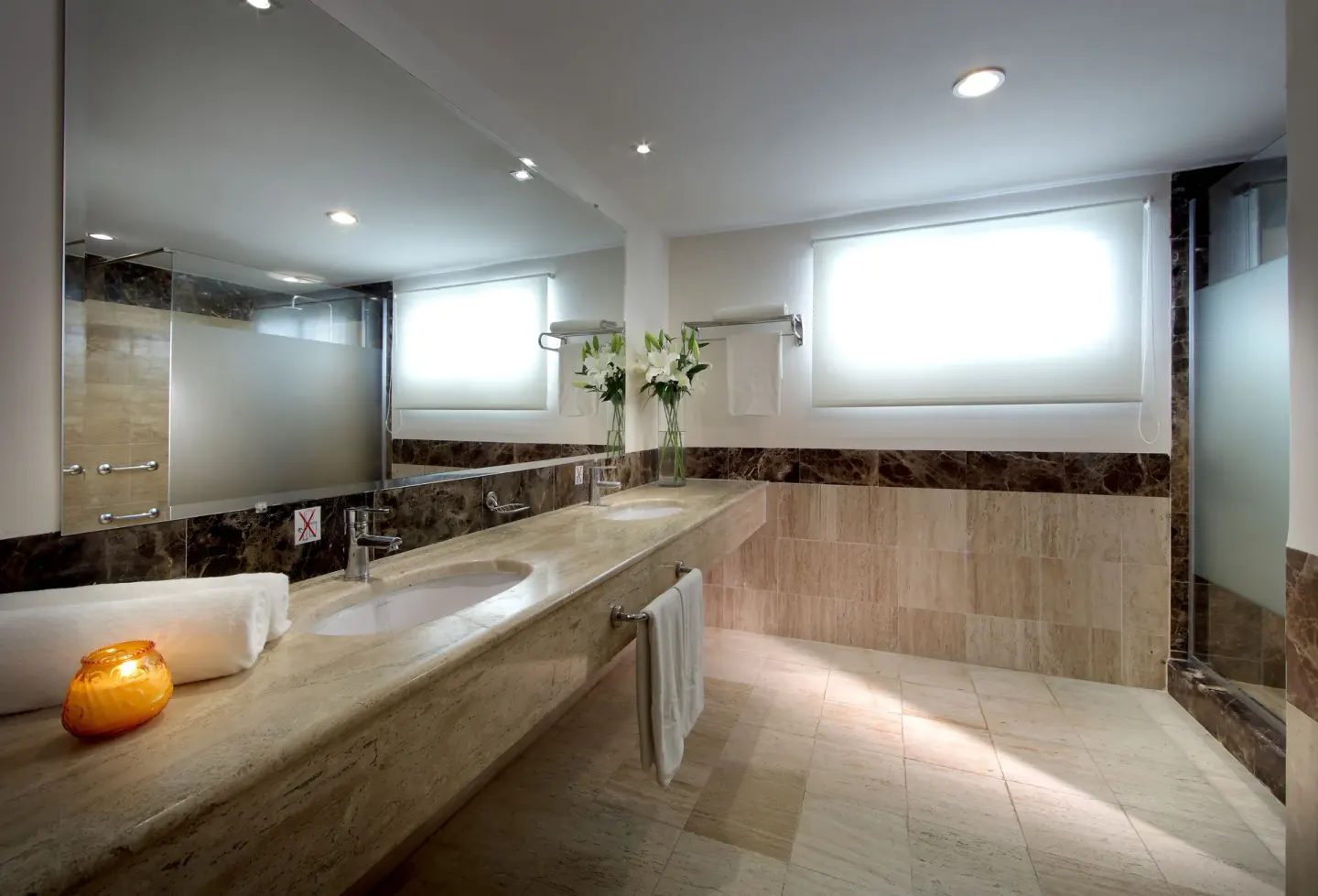 Marble bathroom vanity with frosted-glass shower at TRS Turquesa Hotel.