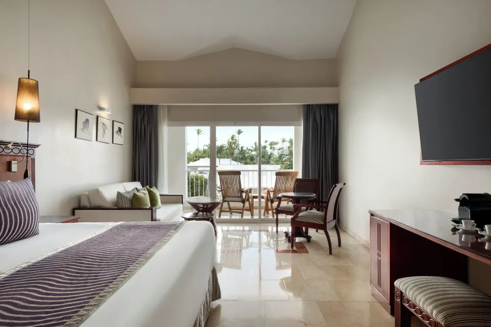 Junior Suite Poolside king bed facing a balcony with palm views at TRS Turquesa Hotel.
