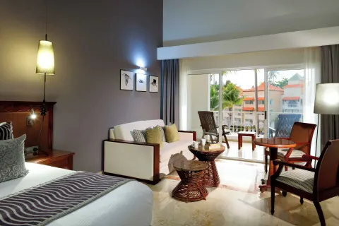 Junior Suite Poolside sitting area with sofa, tables, bed, and balcony at TRS Turquesa Hotel.