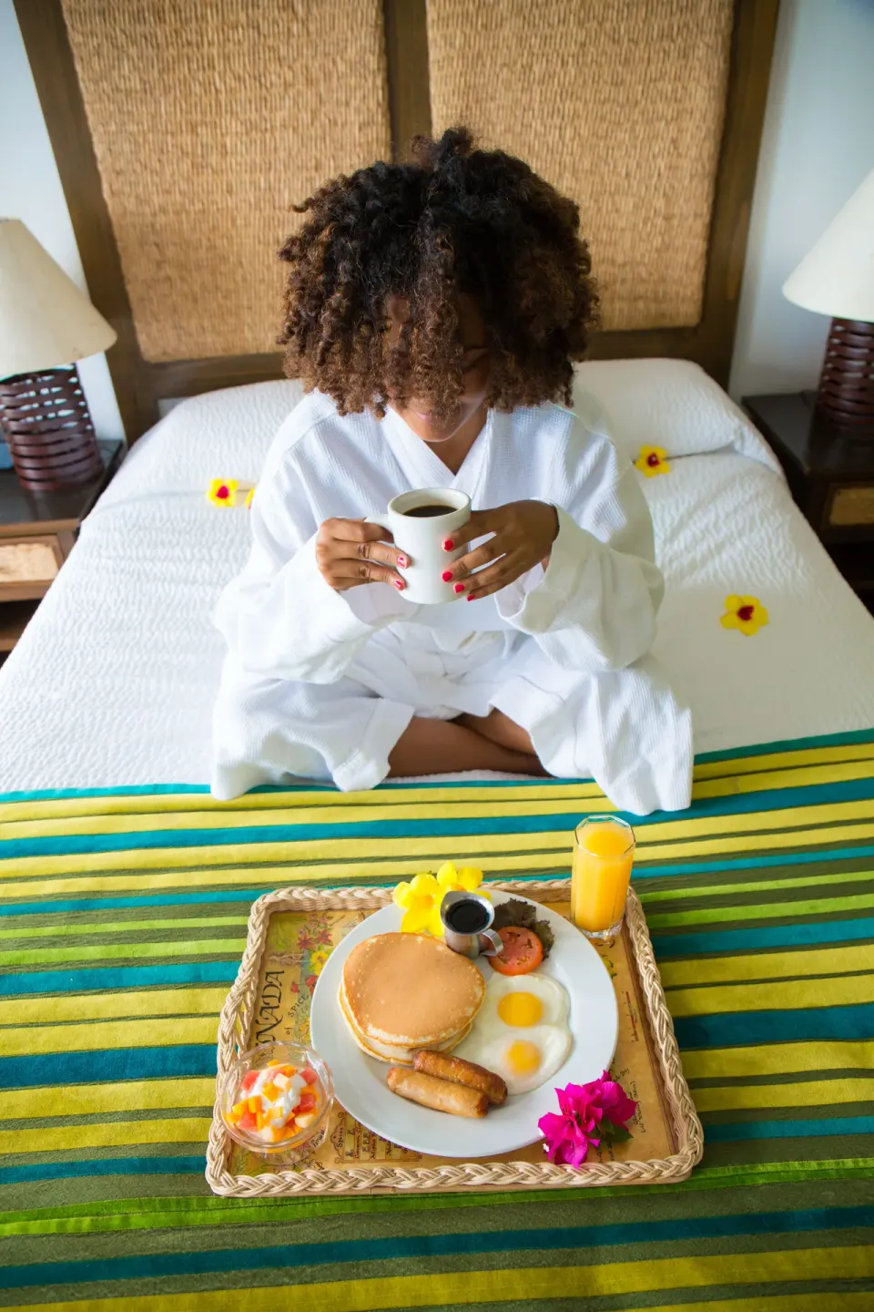 Guest in a robe enjoys breakfast in bed at True Blue Bay Resort.