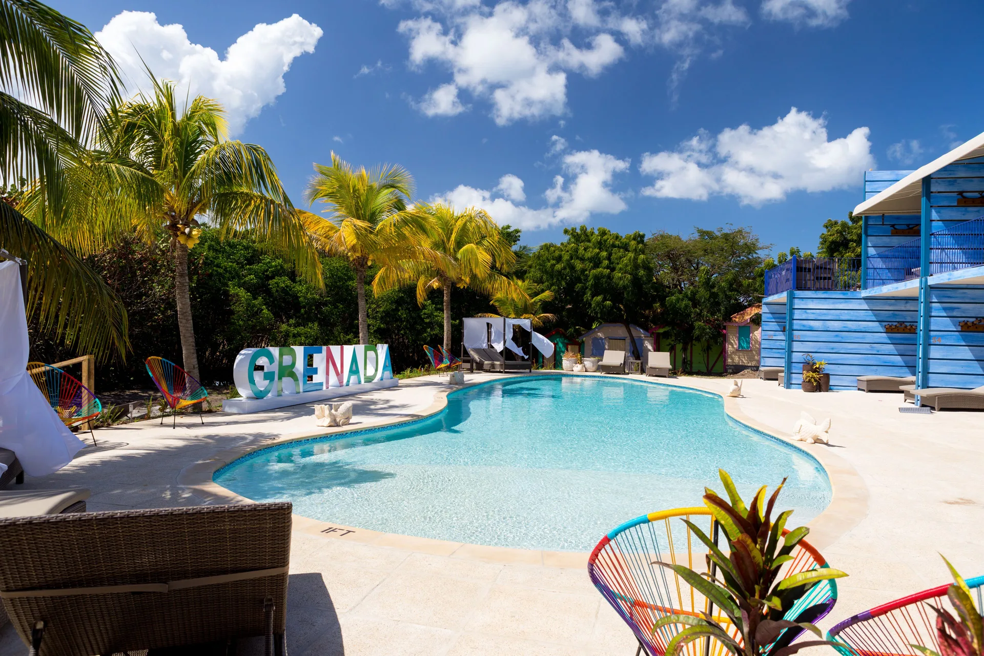 Resort pool with Grenada sign, palms, and blue buildings at True Blue Bay Resort.