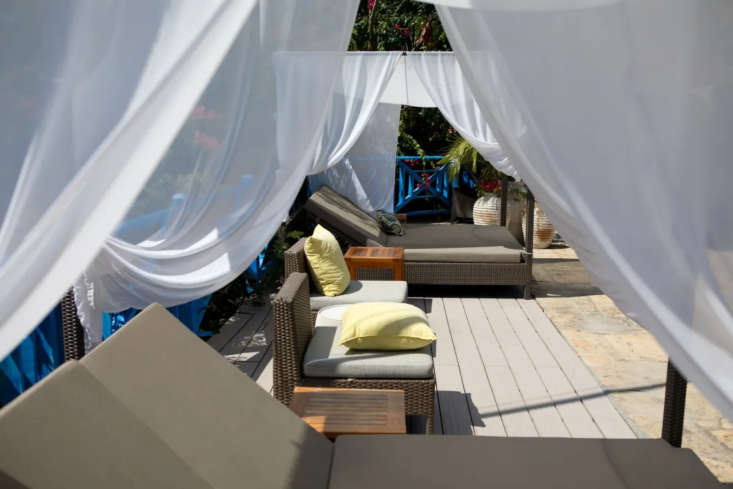White drapes frame outdoor lounge seating on a terrace at True Blue Bay Resort.