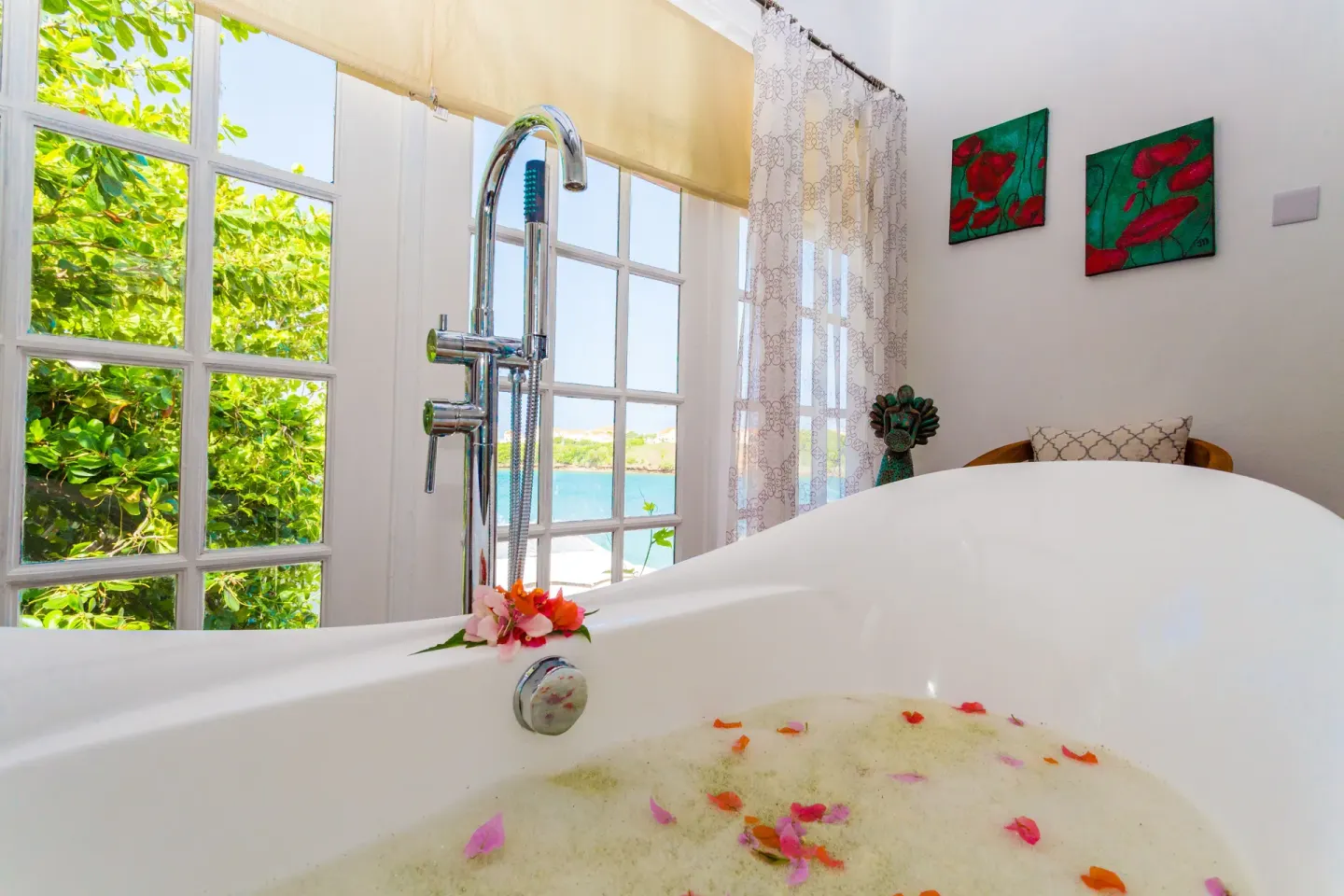 Freestanding bathtub with flower petals by large windows at True Blue Bay Resort.