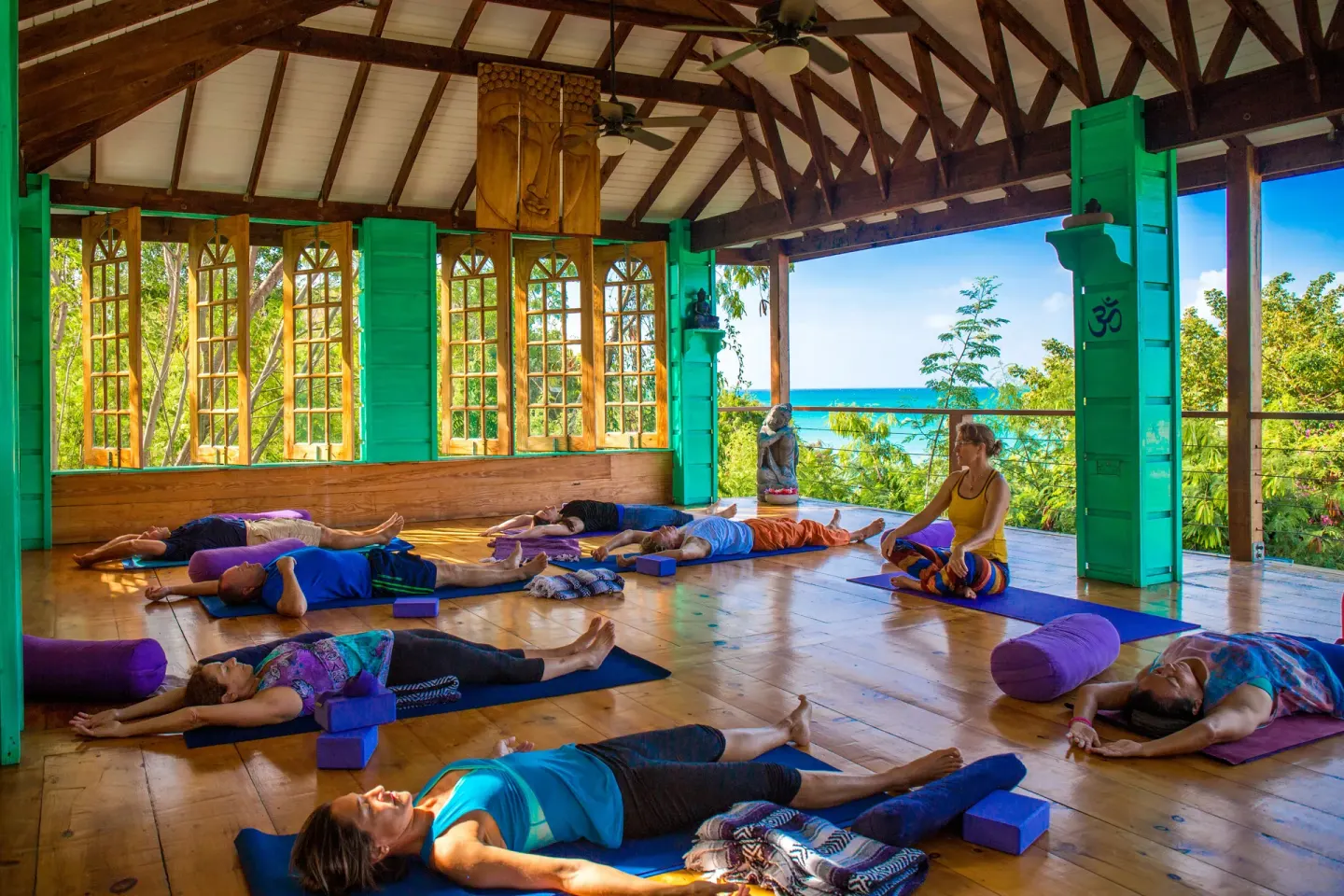 Open-air yoga studio with guests on mats and ocean beyond at True Blue Bay Resort.