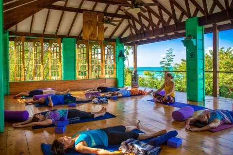 Open-air yoga studio with guests on mats and ocean beyond at True Blue Bay Resort.