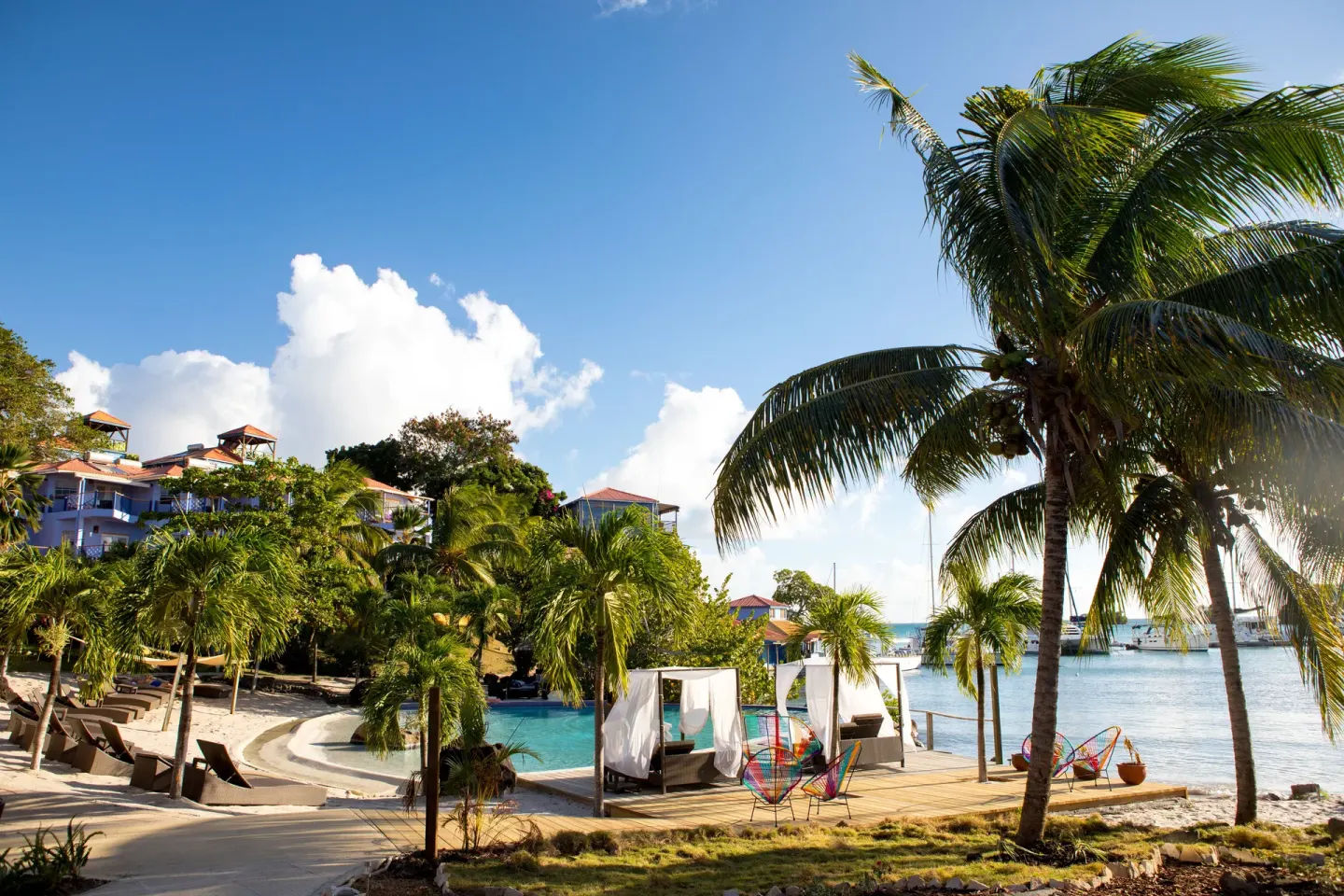 Palm-lined pool and waterfront deck at True Blue Bay Resort.