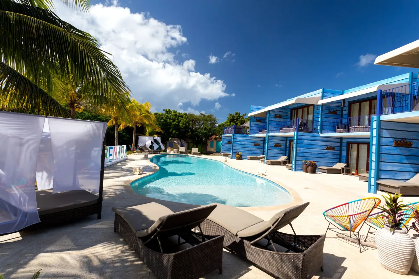 Loungers and a cabana surround the pool by blue buildings at True Blue Bay Resort.